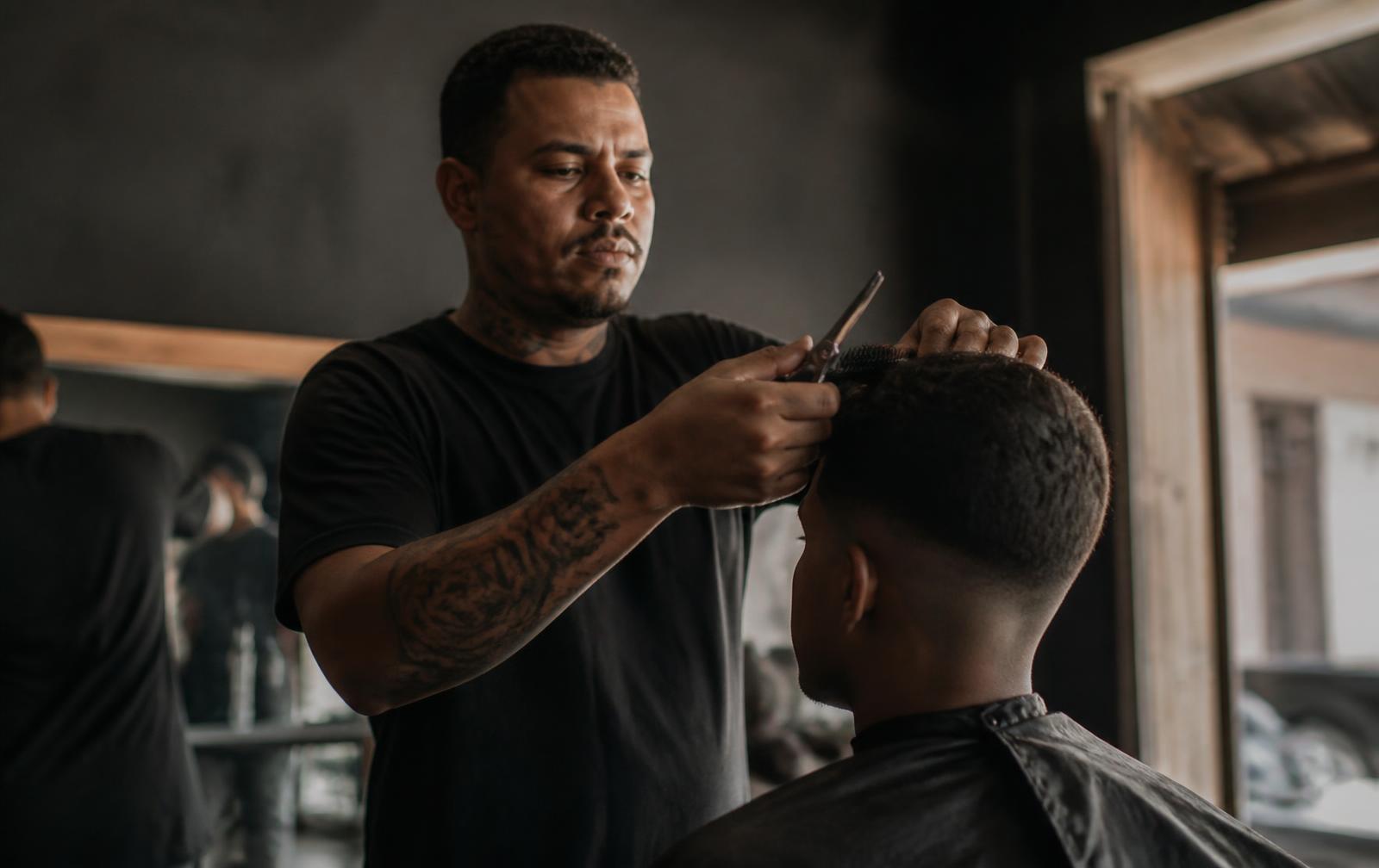 Barbeiro cortando o cabelo de um cliente em uma barbearia de bairro